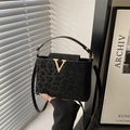 Women's black leopard pattern handbag with golden V-clasp and adjustable shoulder strap - Black