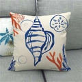 Funda de cojín de lino con diseño de caracola azul y coral sobre sofá gris - Estilo Caracola (3)