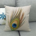 Detailansicht eines quadratischen Leinen-Kissenbezugs mit Pfauenfedermuster auf grauem Sofa - Handgemalter Kunststil Königsblaue Pfauenfeder (11)