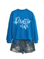Detail of Realtor Life print on blue sweatshirt paired with ripped denim shorts - Lake Blue (White Font)