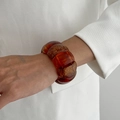 Detailed close-up of an amber resin elastic bracelet with gold leaf flakes and white suit cuff - Amber-0163