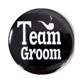Detail of a black Team Groom tin badge with white pipe icon for bachelor parties - Team Groom Pipe Style