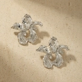 Macro shot of silver orchid flower earrings featuring detailed silk metal textures - Silver