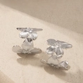 Vue détaillée de boucles d'oreilles fleurs argentées avec texture de pétales ciselés - Or Blanc