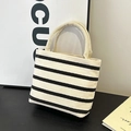 Minimalist black and white striped tote bag with sturdy handles on a wooden table - Off White