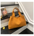 Dettaglio di una borsa tote oversize in feltro arancione su scale moderne interne - Marrone