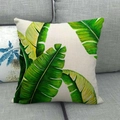 Linen pillow cover with green monstera leaf print on a gray fabric sofa - Tropical Banana Leaf Style (1)