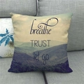 Moderne linnen kussensloop met berglandschap en inspirerende tekst op de grijze bank - Breathe Trust Let Go Bergstijl