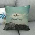 Linnen kussensloop met Explore Mountains print op een grijze stoffen bank - Bergen Verkennen Avontuurlijke Stijl