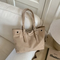 Bolso tote beige con tachuelas y correas ajustables sobre un sofá blanco con estilo - Caqui