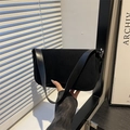 Borsa sottobraccio minimalista in pelle nera opaca con fibbia argento in ambiente moderno - Nero