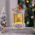 Close-up of a lit Christmas carousel snow globe with swirling glitter and a festive tree - White Tree
