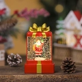 Detailopname van een lichtgevende kerstman sneeuwbol in een rode geschenkverpakking - Rode Kerstman met Zak