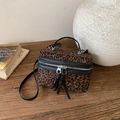 Fashionable leopard print box bag with black leather trim and tassel zippers on wood - Black