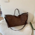 Bolso tote grande de ante marrón oscuro con asas de cuero en un sofá minimalista - Marrón