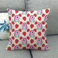 Close-up of linen cushion cover featuring purple dinosaurs and red strawberries on sofa - 45x45cm / Beige Purple Dinosaur Strawberry