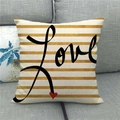 Dettaglio fodera per cuscino in lino con strisce dorate e scritta Love sul divano - Testo Nero Love Cuore Rosso Strisce Oro