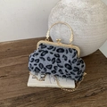 Vintage leopard shell handbag with gold handle and chain strap on a rustic table - Gray