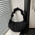 Sac hobo minimaliste en daim noir avec poignée plissée posé sur un rebord de fenêtre - Noir