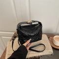 Chic black heart quilted leather handbag with gold metal lock being held by hand - Black