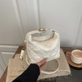 White quilted heart pattern handbag with gold hardware shown in a cozy lifestyle setting - White