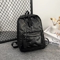 Minimalist black quilted backpack with large front pocket and woven zipper pulls - Black