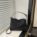 Sac à main minimaliste en suédine noire avec détails dorés sur un rebord de fenêtre blanc - Noir