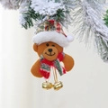 Dettaglio di un orso di Natale in peluche con campanelli su un ramo di pino innevato - Orso