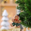 Resin gingerbread man Christmas ornament with green overalls hanging on a festive tree - Suspender Style