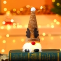 Primer plano de gnomo navideño luminoso con astas de reno sobre un libro verde - Estilo Reno
