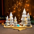Detail von fünf leuchtenden Mini-Weihnachtsbäumen mit Schneebeflockung auf Holztablett - Groß Turmform Set