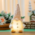 Close-up of glowing LED Christmas gnome with knitted hat and warm light effect - Candy Cane Style