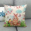 Detail eines Leinen-Osterkissenbezugs mit Hasen- und Blumenprint auf grauem Sofa - Cartoon Kaninchen mit Blumen und Schmetterling (2)
