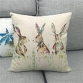 Detail showing watercolor Easter bunnies printed on a beige linen square cushion cover - 45x45cm / Three Painted Watercolor Rabbits