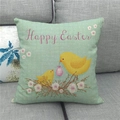 Detail der Leinen-Osterkissenhülle mit Küken und Happy Easter Text auf grauem Sofa - 45x45 cm / Küken Im Nest Stil (1)