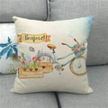 Detail eines Leinenkissenbezugs mit Retro-Fahrrad und Bonjour-Schriftzug auf einem Sofa - Vintage Fahrrad Blumenkorb Stil (1)