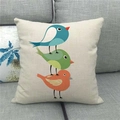 Close-up of linen pillowcase with three colorful cartoon birds on a gray sofa - Blue Green Orange Three Birds Stack (13)