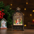 Primer plano de linterna navideña de bronce con bola de nieve LED, muñeco y niños - Estilo de Niño y Muñeco de Nieve