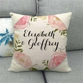 Housse de coussin en lin avec couronne de fleurs et noms personnalisés sur un canapé - Couronne Florale Rose Elizabeth & Geoffrey