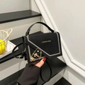 Chic black crossbody bag with suede flap, white stitching, and golden lock on stairs - Black