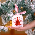 Christmas gift bag with bunny ear knots and red plaid tree pattern held in hand - Christmas Tree