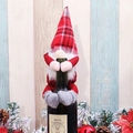 Close-up of red and white plaid gnome wine bottle topper with faux beard and pine decor - Red