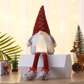 Glowing Christmas gnome plush toy with red knitted hat and warm light on a festive desk - Red