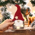 Primer plano de gnomo de Navidad con luces LED y gorro de fieltro rojo decorativo - Gnomo de sombrero rojo