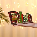 Hand holding a wooden Believe Christmas letter sign with festive plaid patterns and gift box - Horizontal Believe Gift Box Style