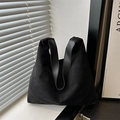 Bolso tote minimalista de cuero negro mate con correa ancha en un ambiente moderno - Negro