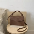 Dark brown woven herringbone shoulder bag with gold hardware on a wooden stool - Brown