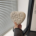 Chic cream heart-shaped quilted mini clutch bag held by hand in a minimalist interior - White