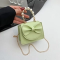 Lime green bow handbag with faux pearl handle and gold chain strap in hand - Green