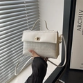 White contrast Kelly bag with geometric texture, top handle, and golden metal swivel lock - White